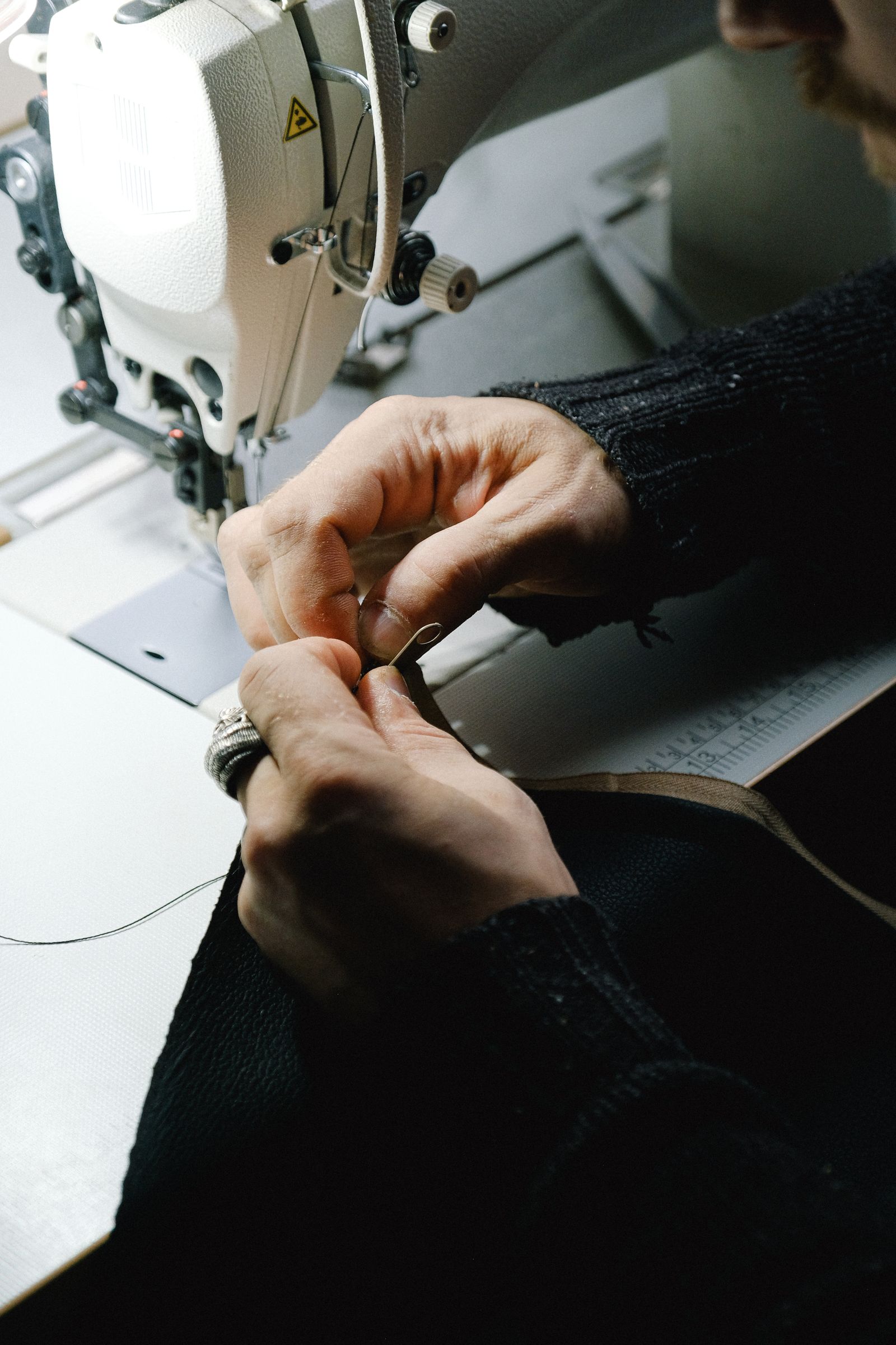 Mãos ajustando um tecido em uma máquina de costura